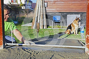 Improvement of the yard, a man evens out the concrete mortar with the rule