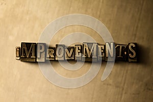IMPROVEMENTS - close-up of grungy vintage typeset word on metal backdrop
