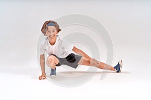 Improving flexibility. Full length of caucasian teenage boy in sportswear stretching legs, warming up before training