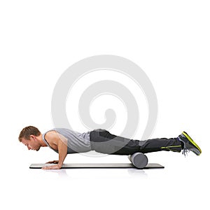 Improving his strength and flexibility. A young man doing push-ups on his exercise mat with his legs raised by a foam