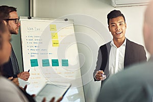 Improving his teams workflow. a young man giving a presentation to colleagues in an office.