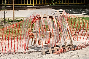 Improvised road construction site barrier with protective caution orange fence or net to protect street reconstruction work ahead