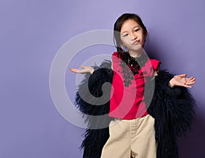 Impudent asian korean kid girl in fashion stylish fur coat and pink t-shirt shows No Words gesture on purple