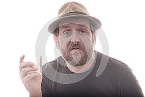 An impudent bearded man in a hat on a white background with a glass in his hand