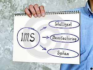 IMS Intelligent Manufacturing System written text. Man showing notepad for notes