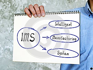 IMS Intelligent Manufacturing System written text. Man showing notepad for notes photo