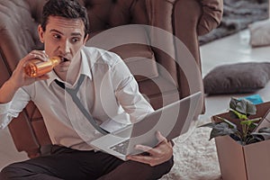 Inaccurate man drinking alcohol in front of a laptop