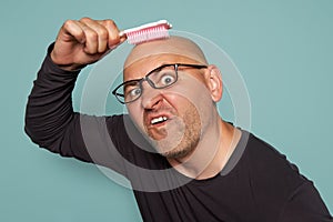 Inadequate man after becoming bald combs his head with a child comb.