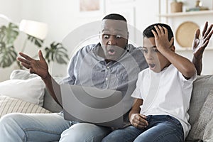 Inappropriate Content. Shocked african grandfather and his grandson looking at laptop screen
