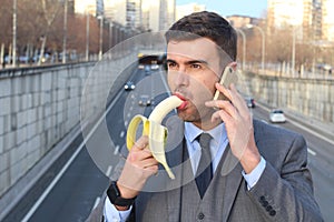 Inappropriate man biting a banana while calling