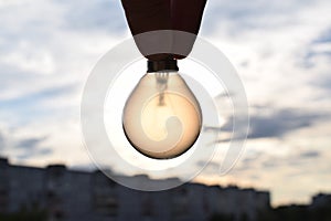 Incandescent bulb in hand against bright sun