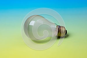 Incandescent burned out light bulb isolated on a green to turquoise blue background with copy space.  It`s horizontal side view