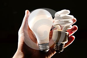 Incandescent and cfl lightbulb in human hand. photo