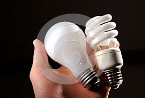 Incandescent and cfl lightbulb in human hand.