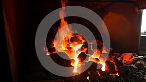 An incandescent furnace in the smithy with coals in which lie red-hot metal parts, heat treatment of details, forge