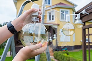 Incandescent lamp in hands close-up. Backyard cleaning