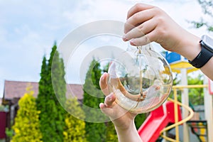 An incandescent light bulb in a childÃ¢â¬â¢s hands, a close-up. Garden cleanup