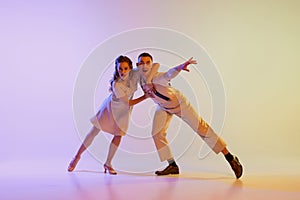 Incendiary dance. Emotional couple of dancers in retro style outfits dancing social dances  on gradient lilac