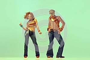 Incendiary dance. Emotional man and woman in retro style clothes dancing disco dance over green background. Concept of