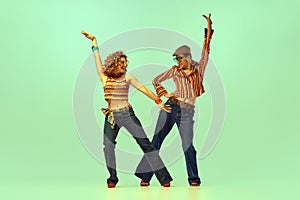 Incendiary dance. Emotional man and woman in retro style clothes dancing disco dance over green background. Concept of