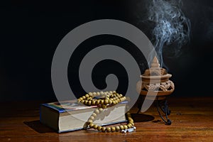 Incense burner and rosary beads on book