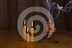 Incense burning in an incense burner with candles on the table for praying Buddha or Hindu gods to show respect.