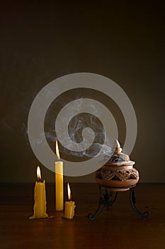 Incense burning in an incense burner on the table with candles.