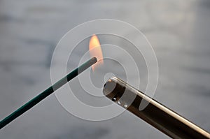 Incense stick being lit with a flame from a lighter