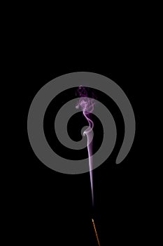 Incense stick with purple smoke trail isolated on black