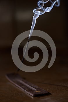 Incense stick smolders and creates smoke and smell
