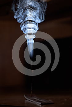 Incense stick smolders and creates smoke and smell