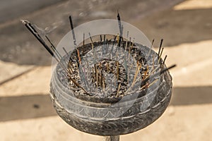 Incense sticks in ashes bucket.