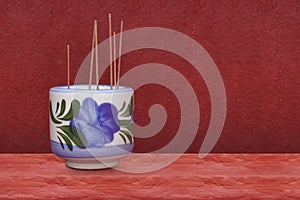 Incense sticks on a ceramic pot on red cement floor, red cement wall background, object, decor, religion, copy space