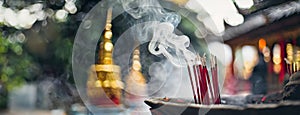 Incense Sticks Emitting Smoke at a Traditional Asian Temple. Incense sticks burn with wisps of smoke rising against a