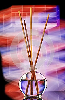 incense sticks in a jar of oil filmed with artificial decorative light