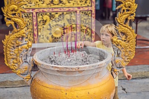 Incense sticks on joss stick pot are burning and smoke use for pay respect to the Buddha, Incense sticks in boy hand and