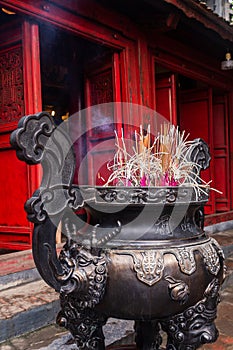 Incense sticks in a steel vase close-up in the Temple of Literature Quoc Tu Giam, Hanoi, Vietnam. Vertical view