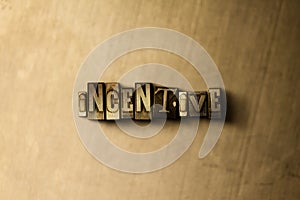 INCENTIVE - close-up of grungy vintage typeset word on metal backdrop