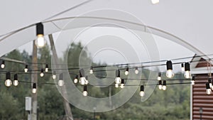 Included string of light bulbs on black wire hangs under the roof of white tent