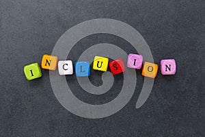 Inclusion text of multi colored cubes on dark background. Inclusive social concept photo