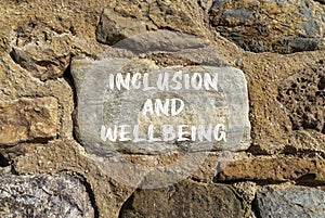 Inclusion and wellbeing symbol. Concept words Inclusion and wellbeing on beautiful big stone on stone wall. Beautiful stone wall