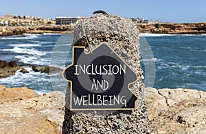 Inclusion and wellbeing symbol. Concept words Inclusion and wellbeing on beautiful black chalk blackboard. Beautiful stone sea sky