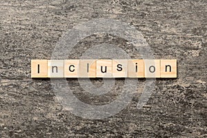 Inclusion word written on wood block. Inclusion text on cement table for your desing, concept