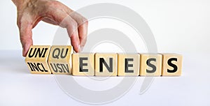 Inclusiveness and uniqueness symbol. Businessman turns wooden cubes, changes words inclusiveness to uniqueness. Beautiful white