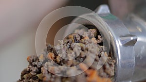 An incognito woman cooks meat in a home kitchen. Minced meat on a manual mechanical meat grinder