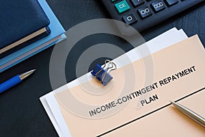 Income contingent repayment plan near calculator and notepads. photo