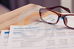 Income statement letter on brown envelope and eyeglass, business