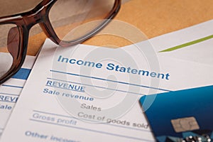 Income statement letter on brown envelope and eyeglass, business photo