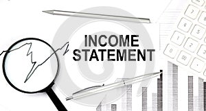 INCOME STATEMENT text on document with pen,graph and magnifier,calculator