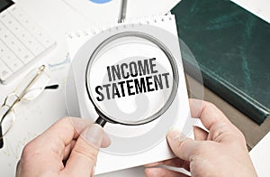 INCOME STATEMENT text on the document with pen,graph and magnifier,calculator